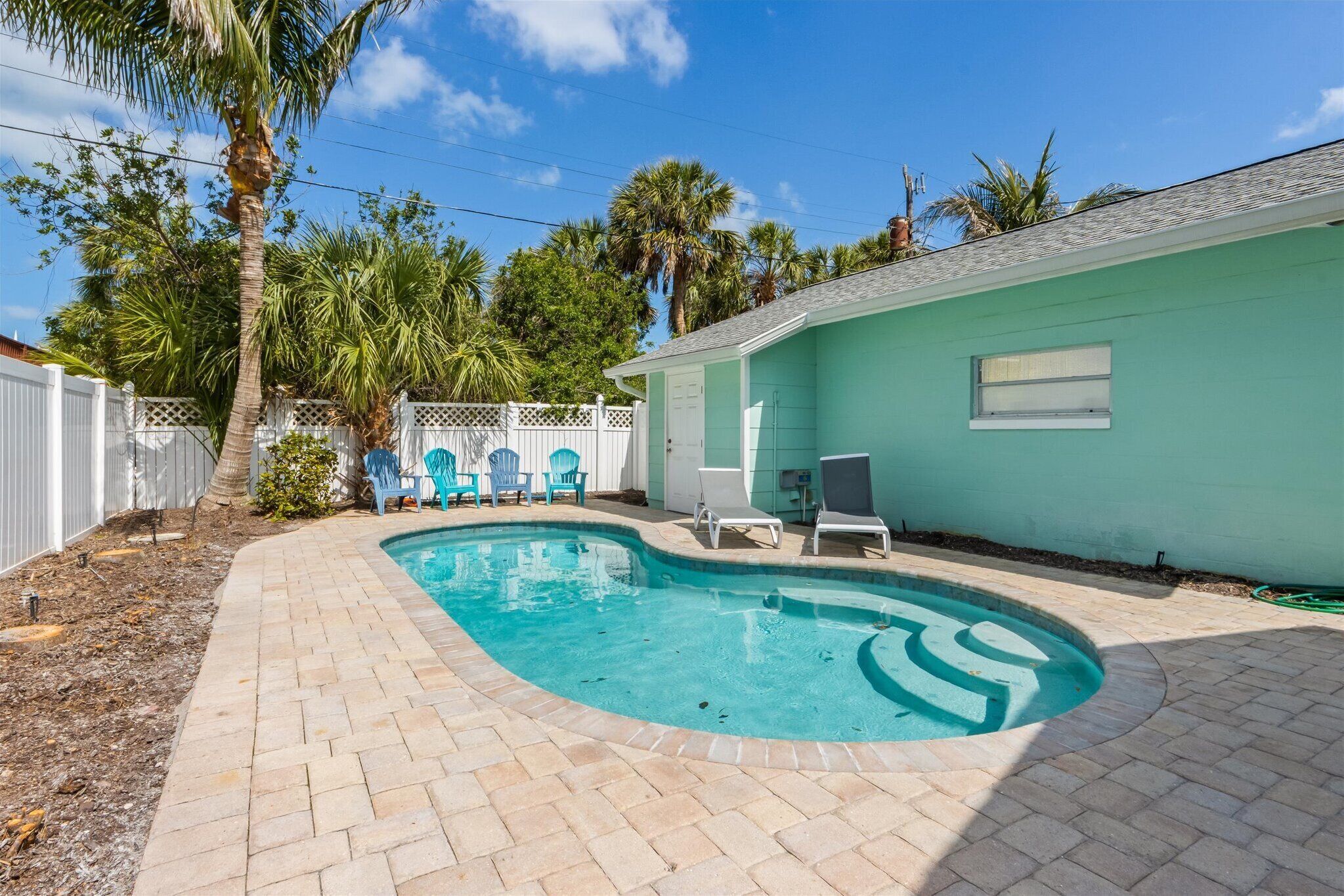 A swimming pool with a curved edge, surrounded by a brick patio.