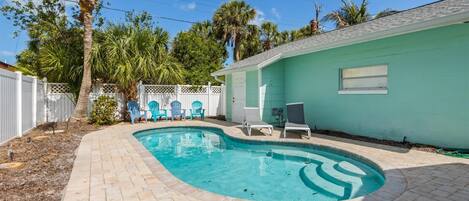 A swimming pool with a curved edge, surrounded by a brick patio.