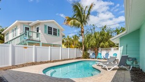 A backyard with a swimming pool, a white fence, and a house with a balcony. - Sea Spray 4: *Heated Pool *Pet-Friendly *Steps to beach *Shops, dining close (Anna Maria)