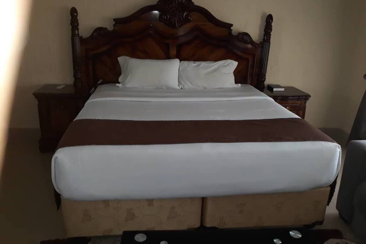 A neatly made bed with a wooden headboard, two bedside tables, and a chair.