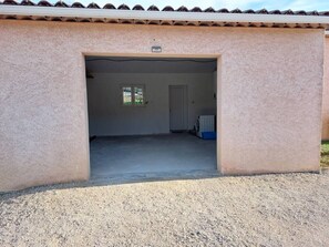A building with a large open garage entrance, a small window, and a door.