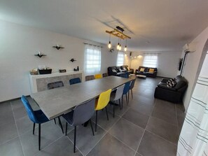 A modern kitchen with a dining area, featuring a long table, chairs, and a built-in bench.