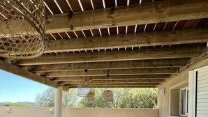 An outdoor patio with wicker furniture, a pergola, and a view of the landscape. - Villa Ghjulia (Porto-Vecchio)