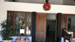 A wooden door with glass panels and a red bow decoration. There are potted plants and vases on the floor.