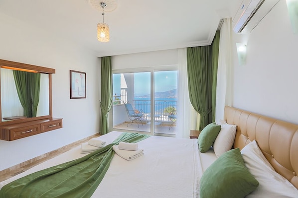 Une chambre d’hôtel avec un lit, un balcon offrant une vue, un luminaire au plafond et un climatiseur fixé au mur.
