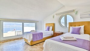 Une chambre d’hôtel avec deux lits, un balcon offrant une vue agréable et un miroir rond accroché au mur.