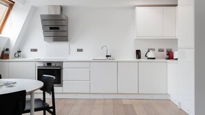 A modern kitchen with white cabinetry, a built-in oven, and a skylight.