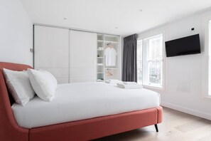 Une chambre d’hôtel moderne avec un grand lit, une armoire, une télévision et une fenêtre avec des rideaux.