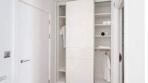 A white walk-in closet with open doors, shelves, and hanging space.