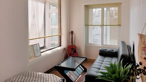 A living room with a sofa, a glass coffee table, a guitar, and a plant. - Cheese Guesthouse - Hostel (Seoul)
