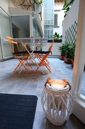 A small outdoor seating area with a table and chairs, a candle in a lantern, and potted plants. - Napoli a Festa (Naples)