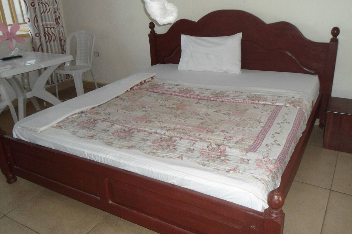 A bed with a floral bedspread, a white pillow, and a wooden headboard.
