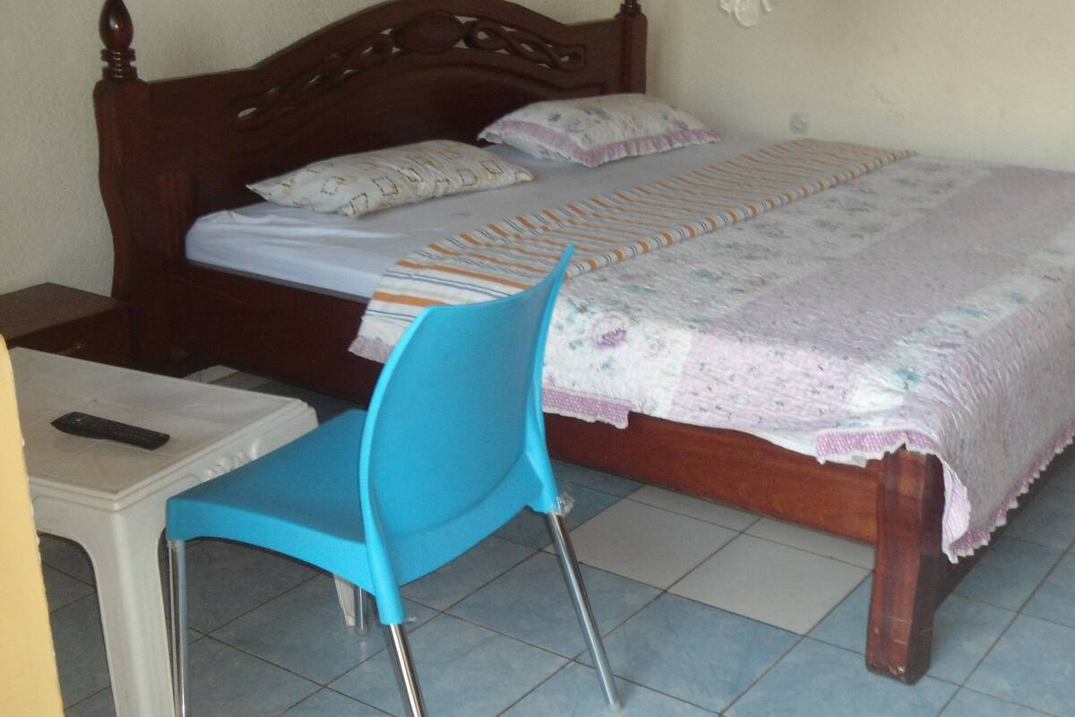 A bedroom with a wooden bed, a blue chair, and a small bedside table.