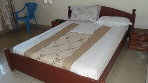 A neatly made bed with a floral bedspread and a wooden headboard. - Airport luxury motel (Kigali)