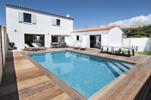 Une maison moderne dotée d’une piscine, de mobilier d’extérieur et d’un espace patio.