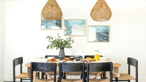 A dining area with a wooden table, black chairs, and woven pendant lights.