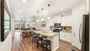 A modern kitchen with a central island, bar stools, pendant lighting, and a view to the outdoors. - Sleeps 16 w/ 4 Kings - Bunk Loft on the 18th Hole (St. George)