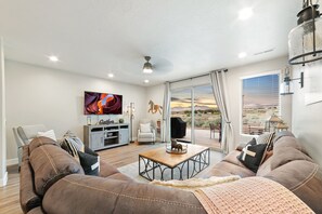 A living room with a sofa, coffee table, TV, and a view of the outdoors.