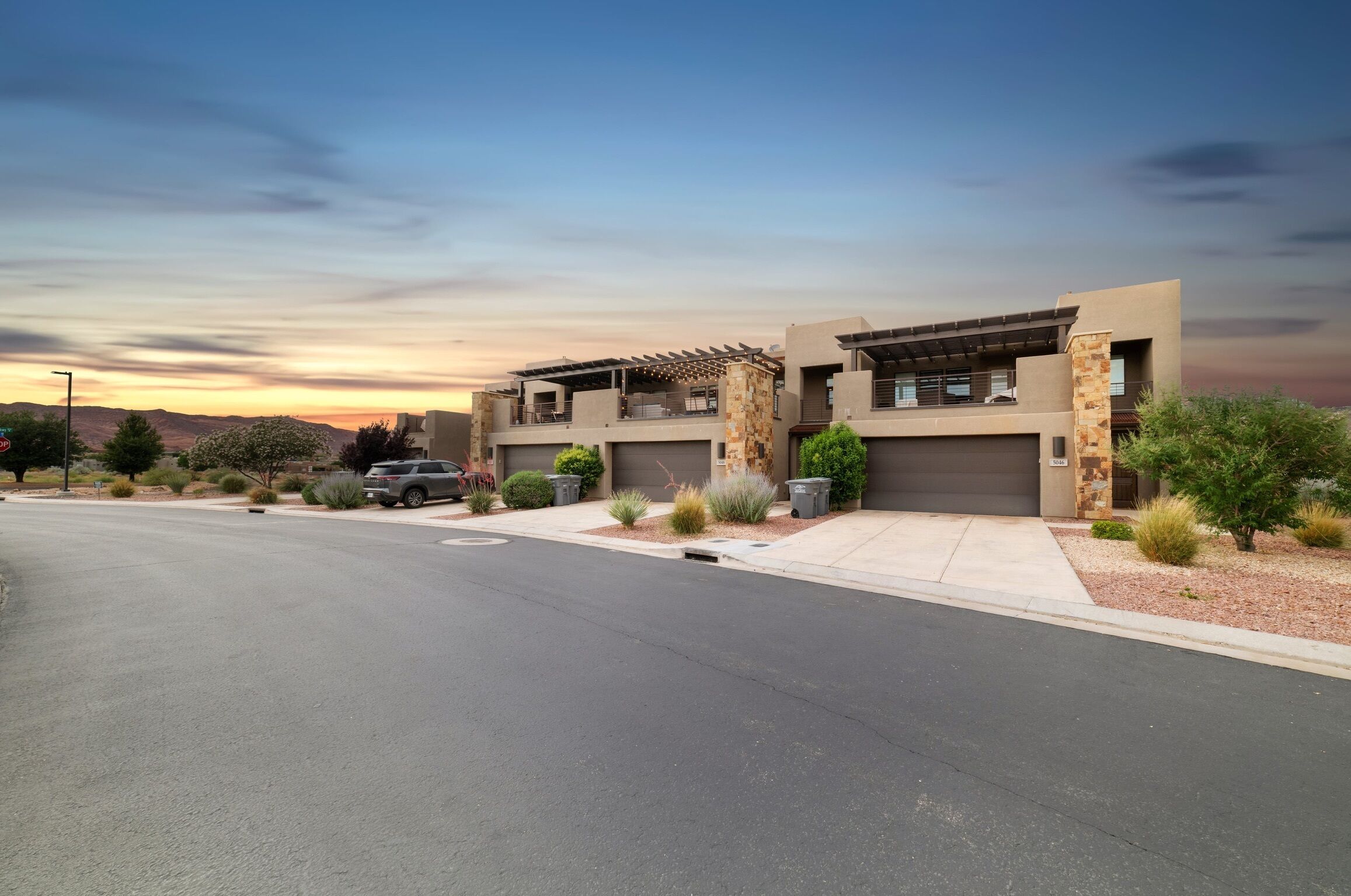 A modern two-story house with a garage, a driveway, and a landscaped front yard.