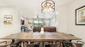 A dining area with a wooden table, metal chairs, a hanging light fixture, and a view of a living room with a brown sofa and a vase. - Sleeps 16 w/ 4 Kings - Bunk Loft on the 18th Hole (St. George)