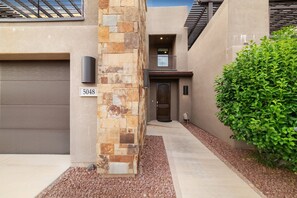 A modern house with a stone facade, a garage, and a well-maintained garden.
