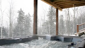 Ein Whirlpool mit Blick auf einen verschneiten Wald.