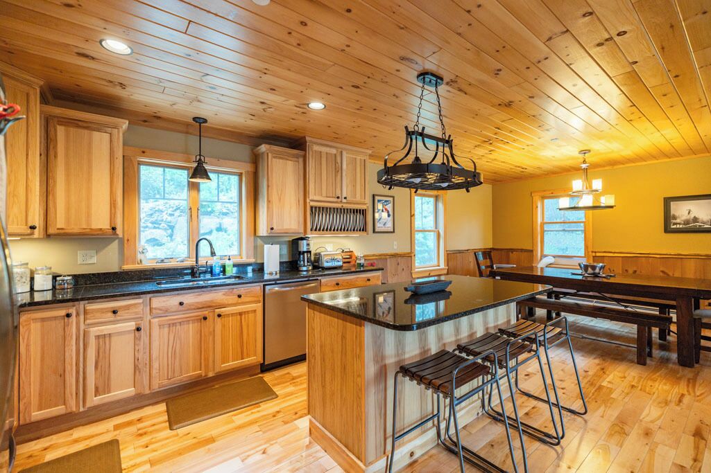 Una cocina amplia con armarios de madera, una isla central y taburetes de bar.