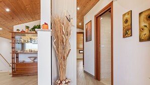 A hallway with wooden flooring, a white column with a vase, and a wooden cabinet with glassware. - If you dream it, you can make it come true.Relax and enjoy the unique experience of VillaLena (Siracusa)