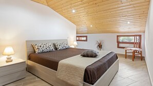 A bedroom with a wooden ceiling, a bed with patterned pillows, a nightstand with a lamp, and a window with a view. - If you dream it, you can make it come true.Relax and enjoy the unique experience of VillaLena (Siracusa)