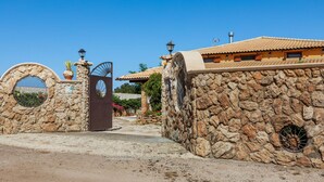 A stone-walled building with a traditional tiled roof, a metal gate, and a clear blue sky. - If you dream it, you can make it come true.Relax and enjoy the unique experience of VillaLena (Siracusa)