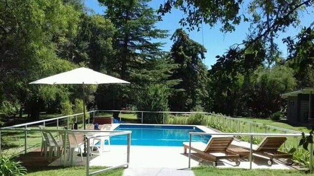 Um quintal com piscina, varanda coberta e um caminho até a piscina.