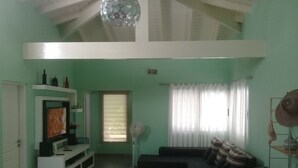 Sala de estar com televisão, sofá e ventilador.