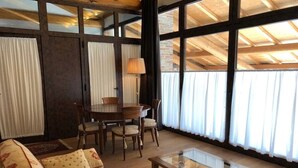 Amplia sala de estar con un ventanal, comedor con mesa y sillas, y sofá tapizado con motivos florales.