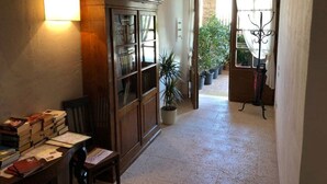 Un pasillo con un aparador de madera, un escritorio con libros y una planta en maceta.
