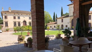 Un patio con mobiliario exterior, vistas a un edificio histórico y un jardín bien cuidado.