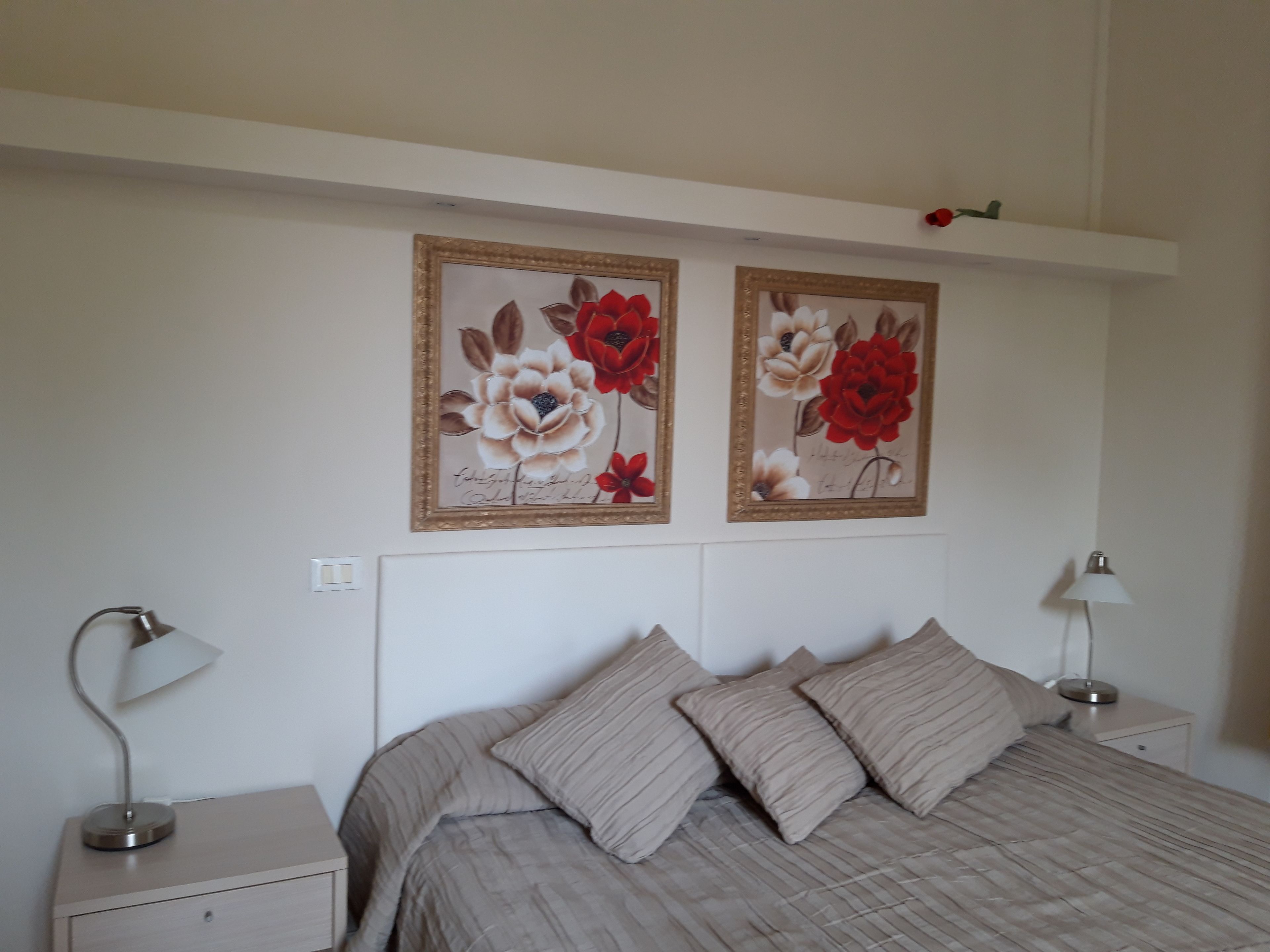Un dormitorio con una cama, dos mesitas de noche y dos lámparas de pared.