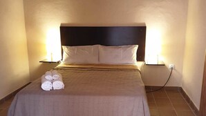Ein ordentlich bezogenes Bett mit Kopfteil, zwei Nachttischlampen und aufgerollten Handtüchern auf dem Bett.