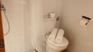 Ein kleines, sauberes Badezimmer mit Toilette, Dusche und Waschbecken.