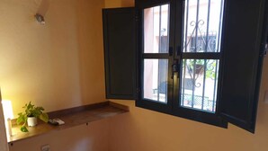 Ein kleines Badezimmer mit Fenster, Handtuchhalter und einer Topfpflanze.
