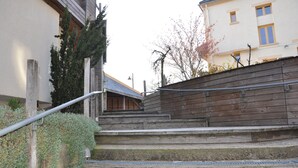 A set of concrete steps leading up to a wooden wall with a metal handrail. - Le Relais des Lacs (Planchez)