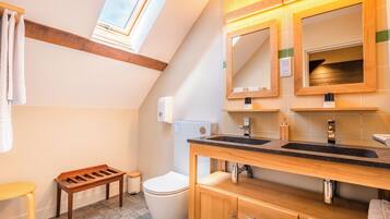 A modern bathroom with a skylight, wooden vanity, and a toilet.