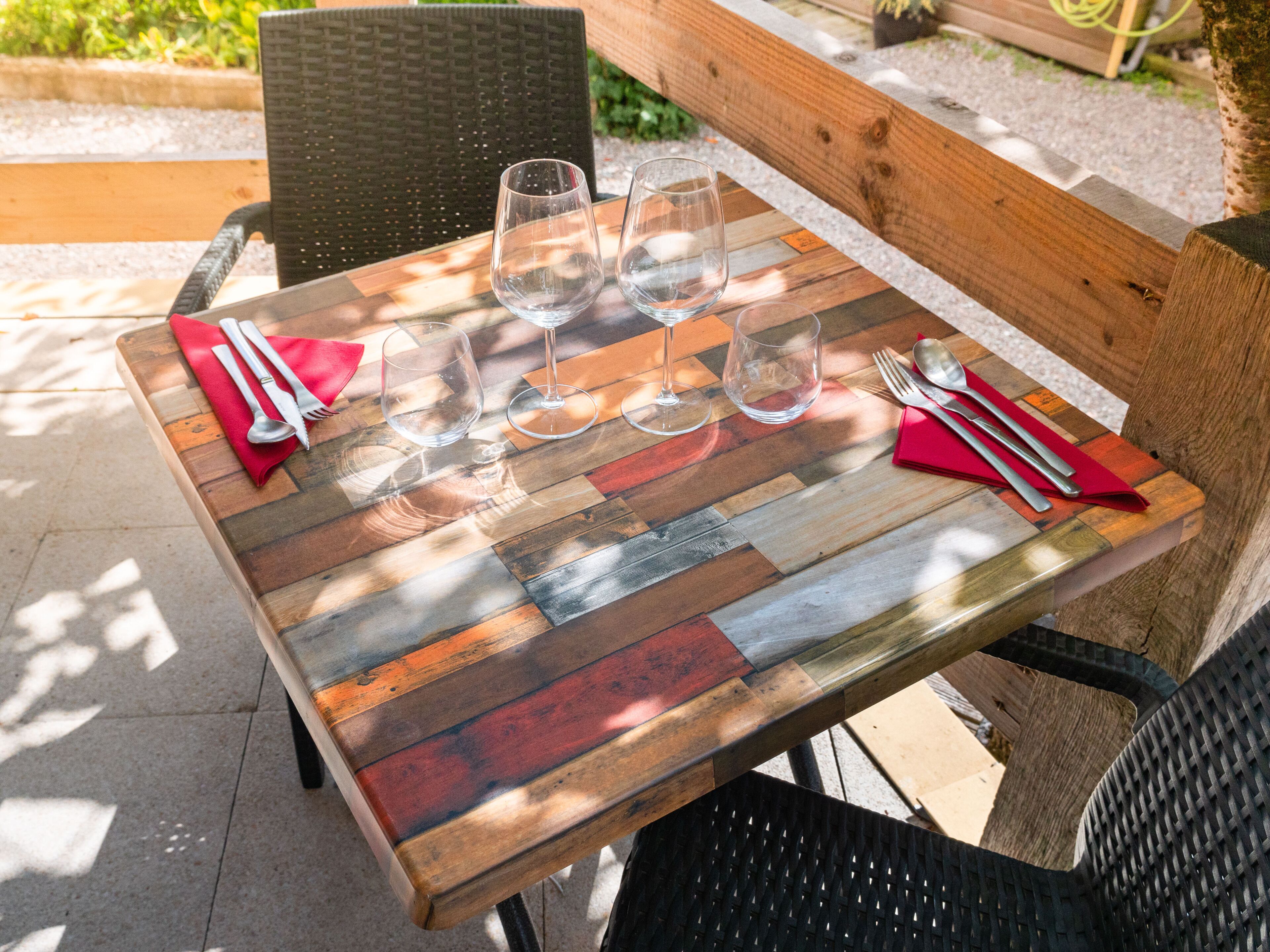 Una mesa de madera de diseño rústico, ubicada al aire libre con un banco y sillas alrededor.