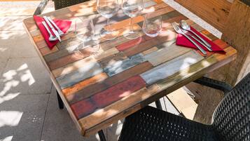 Una mesa de madera de diseño rústico, ubicada al aire libre con un banco y sillas alrededor.