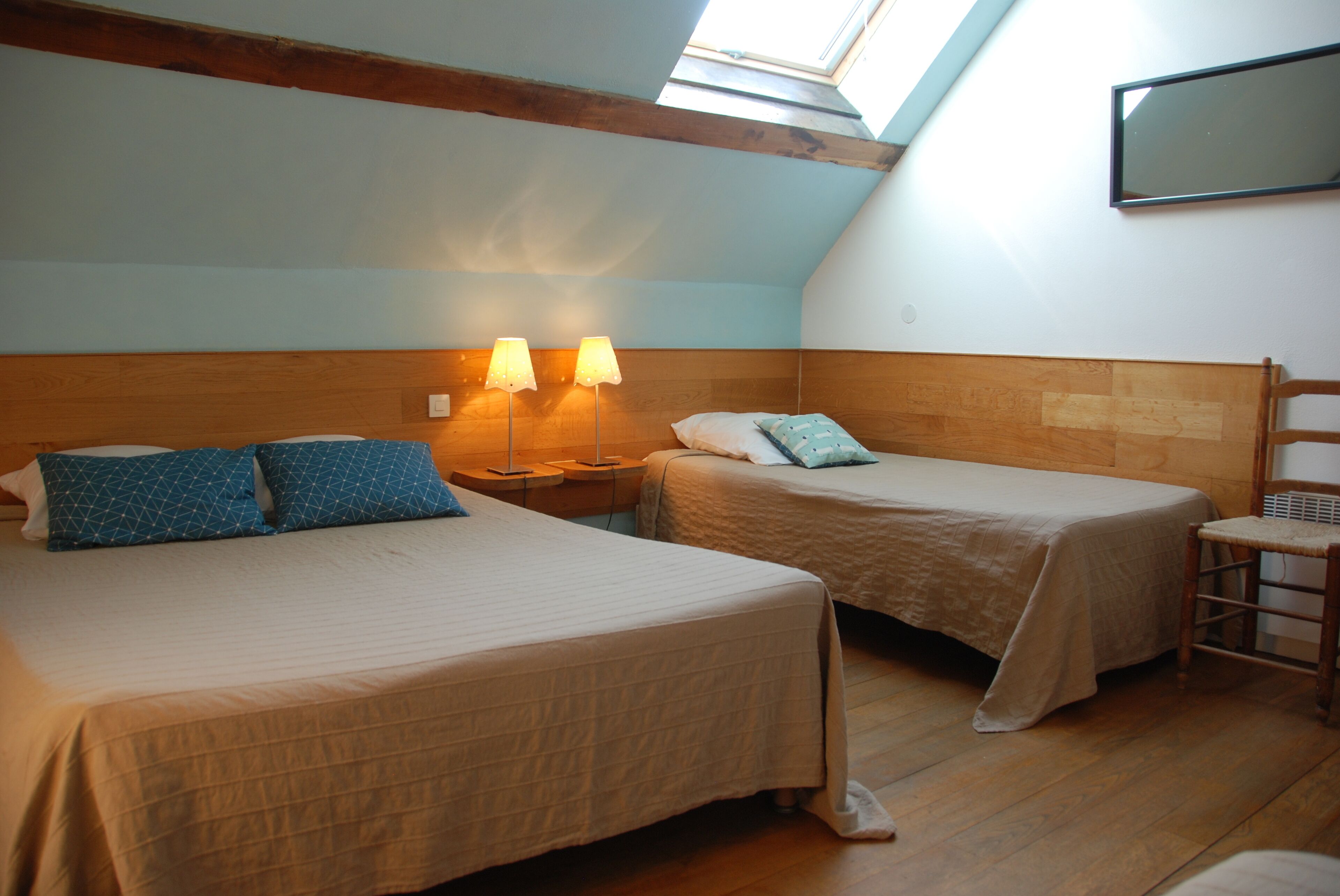 A room with two beds, wooden headboards, and a skylight.