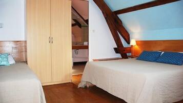 A bedroom with a wooden wardrobe, a bed with a headboard, and a nightstand with a lamp.