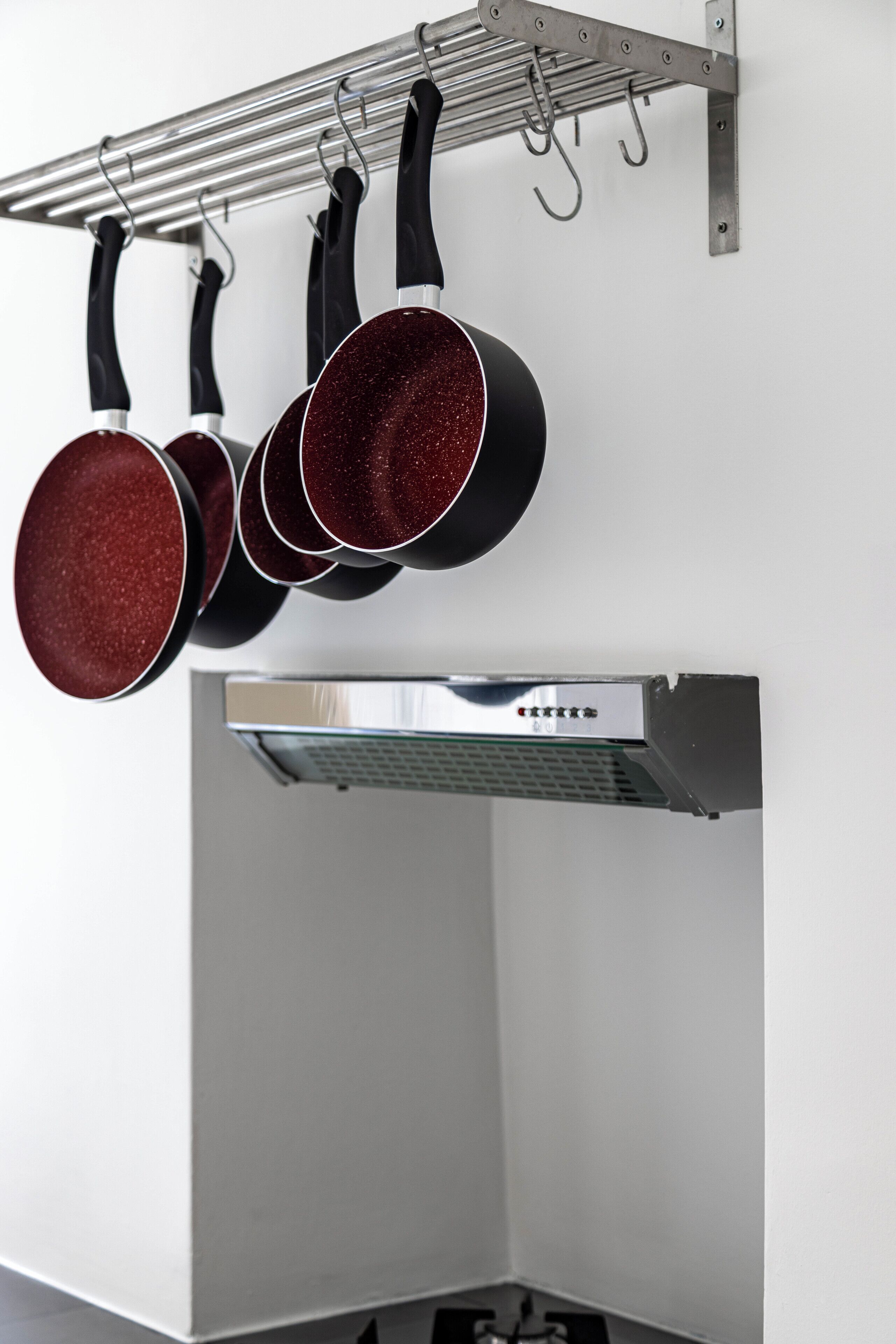 Uma cozinha com panelas penduradas e um exaustor de aço inoxidável.