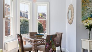 Un espace repas comprenant une table, des chaises et un fauteuil décoré sur le thème du paon.