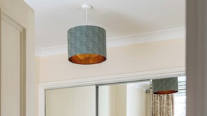 Une chambre d’hôtel dotée d’un grand miroir, de deux lits avec une literie jaune et blanche, d’une tête de lit verte et d’un luminaire suspendu.