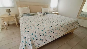 Une chambre à coucher avec un lit, une table de chevet, une lampe et une fenêtre.