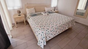 Ein Schlafzimmer mit einem Bett, einem Nachttisch, einer Lampe und einer Wand-Klimaanlage.